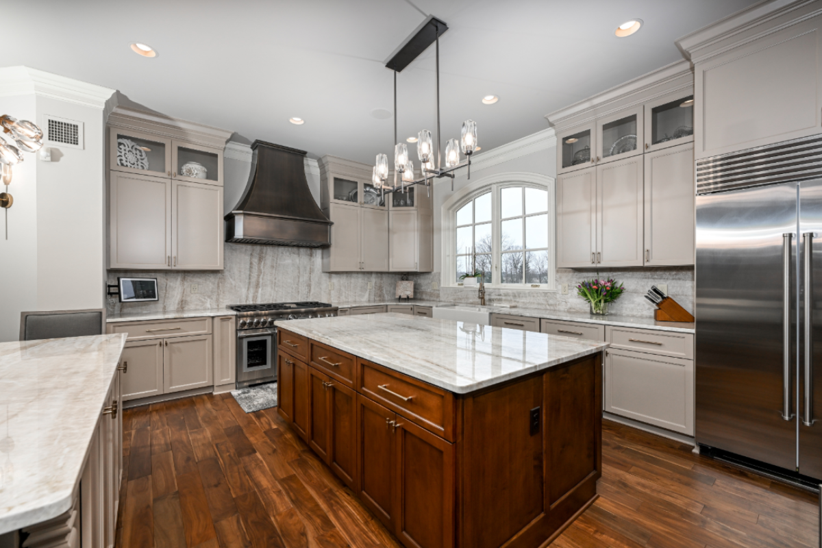 A bright family kitchen with stainless steel appliances, champagne bronze cabinet pulls on shaker cabinets, and light quartz counters in daylight