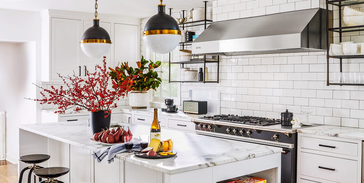 A bright kitchen with cool white walls, stainless steel appliances, pale stone countertops, and morning daylight coming through a window