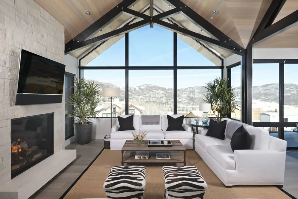 A bright open concept living room with a large sectional and a coffee table, all arranged on a generously sized area rug that defines the seating zone, real photo