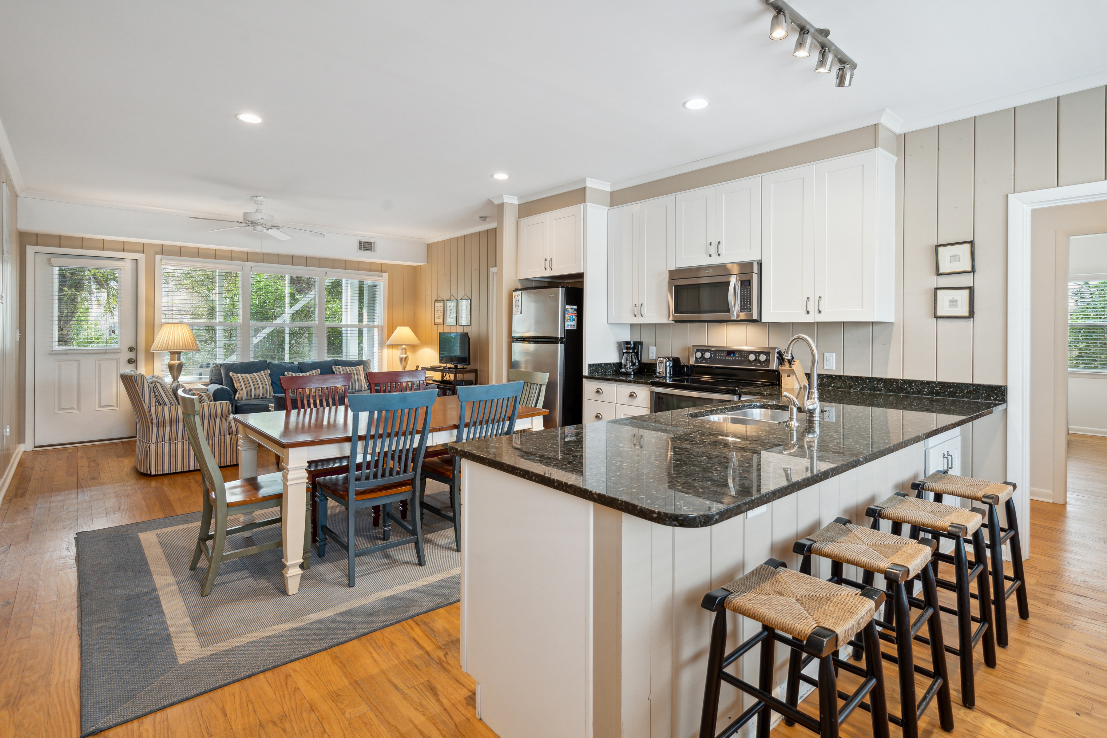 A bright rental kitchen with sunlight streaming through a window onto an older sheet floor, with a simple neutral runner placed near the sink, realistic photo