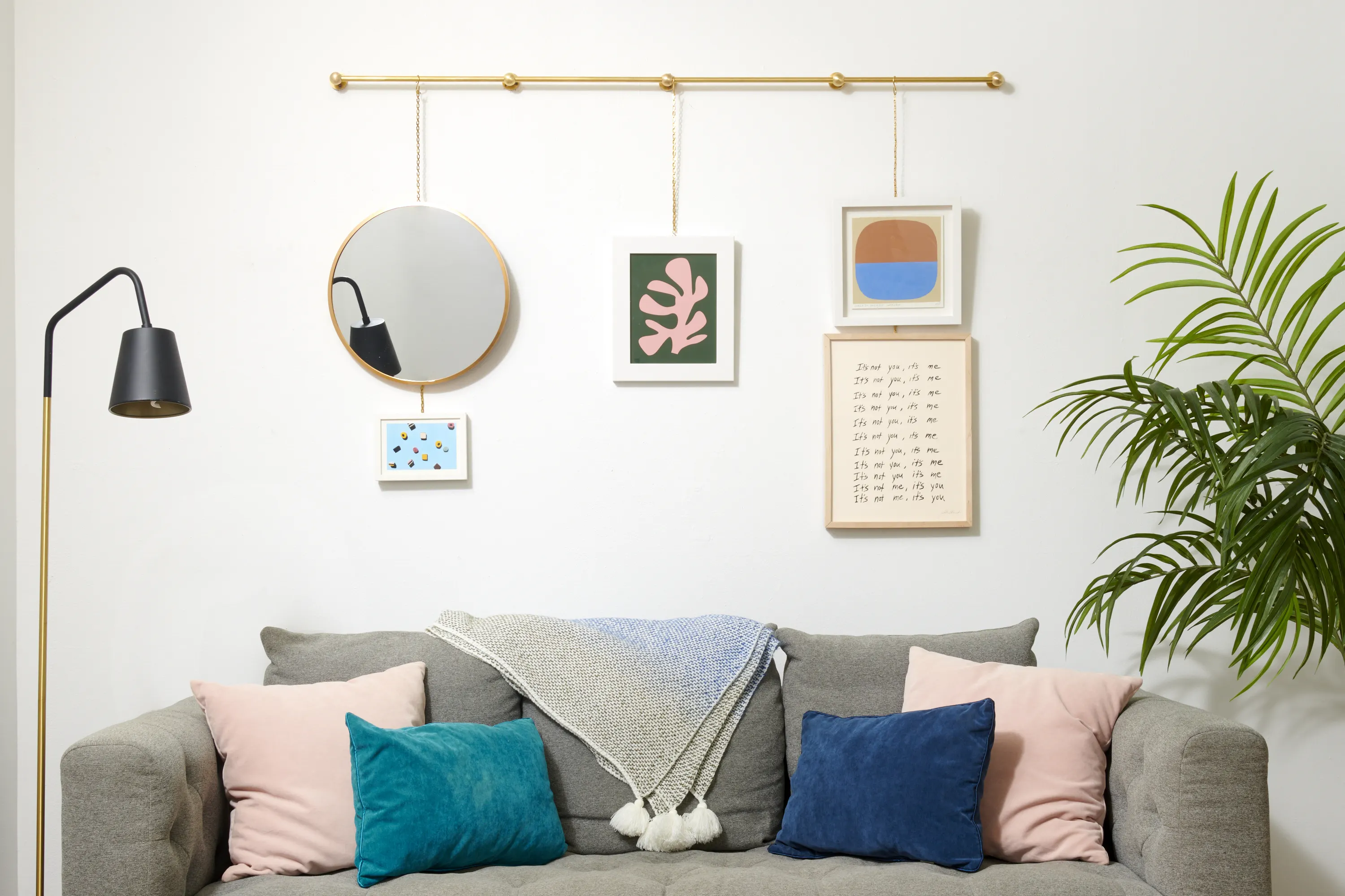 A close-up of a wall-mounted picture rail with hooks and clear hanging cords holding framed artwork, real photograph