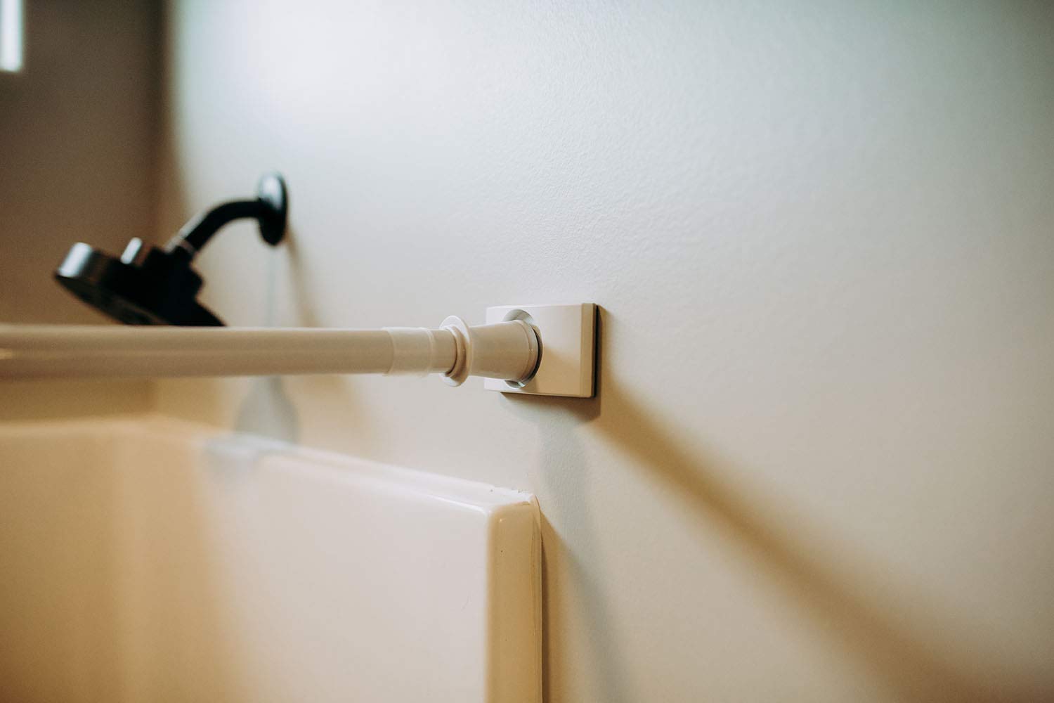 A close-up photo of a clear rubber tension rod pad pressed against glossy subway tile with a shower curtain rod end cap seated on it