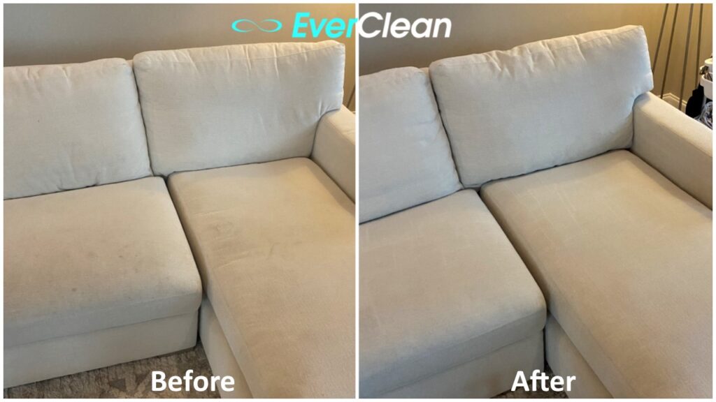 A close-up real photo of a fabric sofa seat with deep button tufting while a narrow crevice vacuum tool hovers over a tuft well, showing textured weave and visible lint in the seams