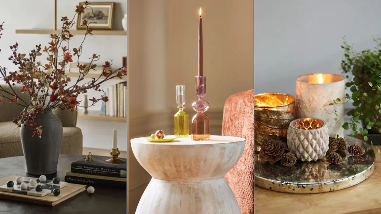 A coffee table styled for fall with an amber glass vase, a small brass candlestick, a stack of books, and a wooden tray, soft golden afternoon light