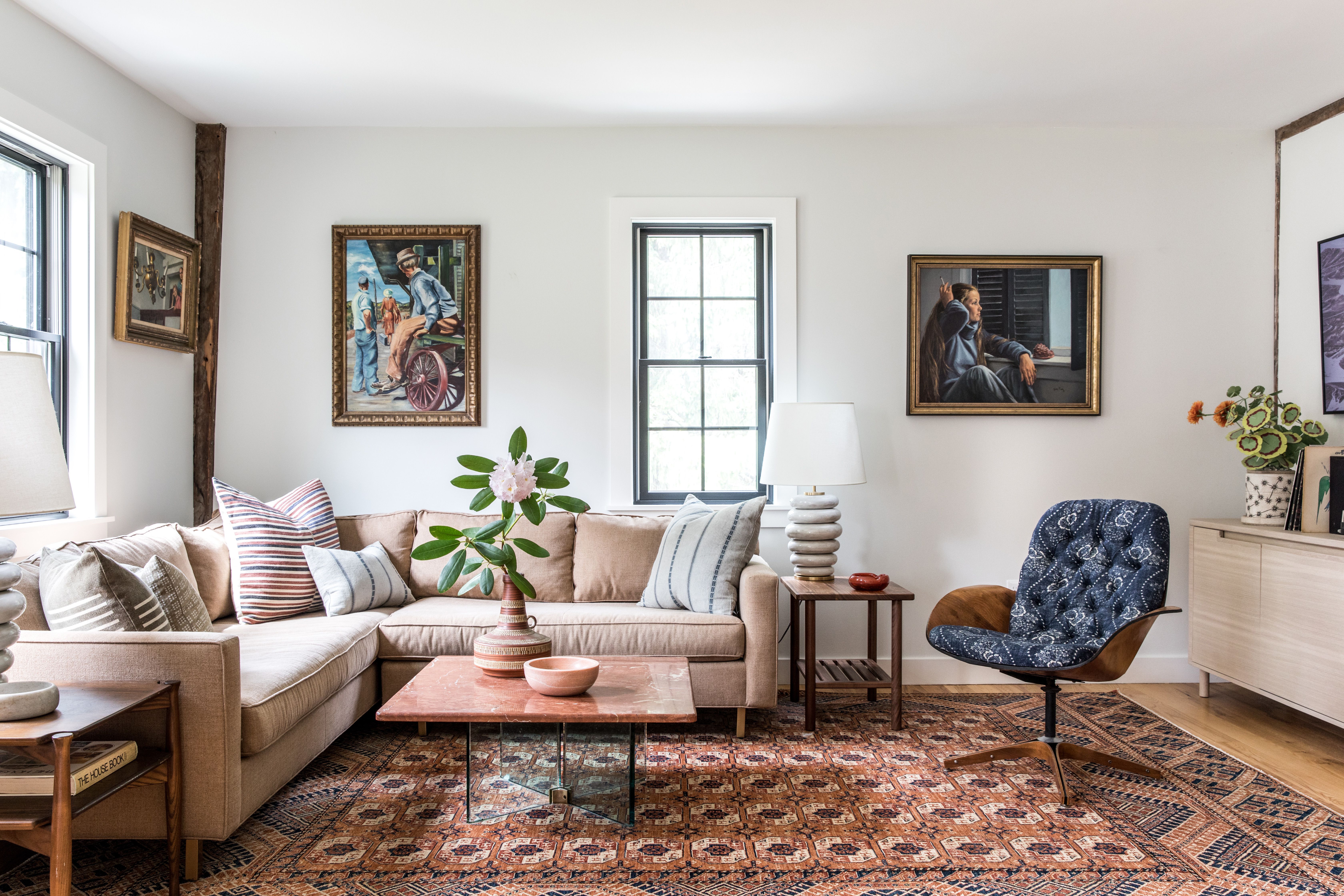 A cozy living room with a textured neutral rug bridging a light wood floor and a darker wood coffee table, with linen curtains and a warm table lamp, real photography