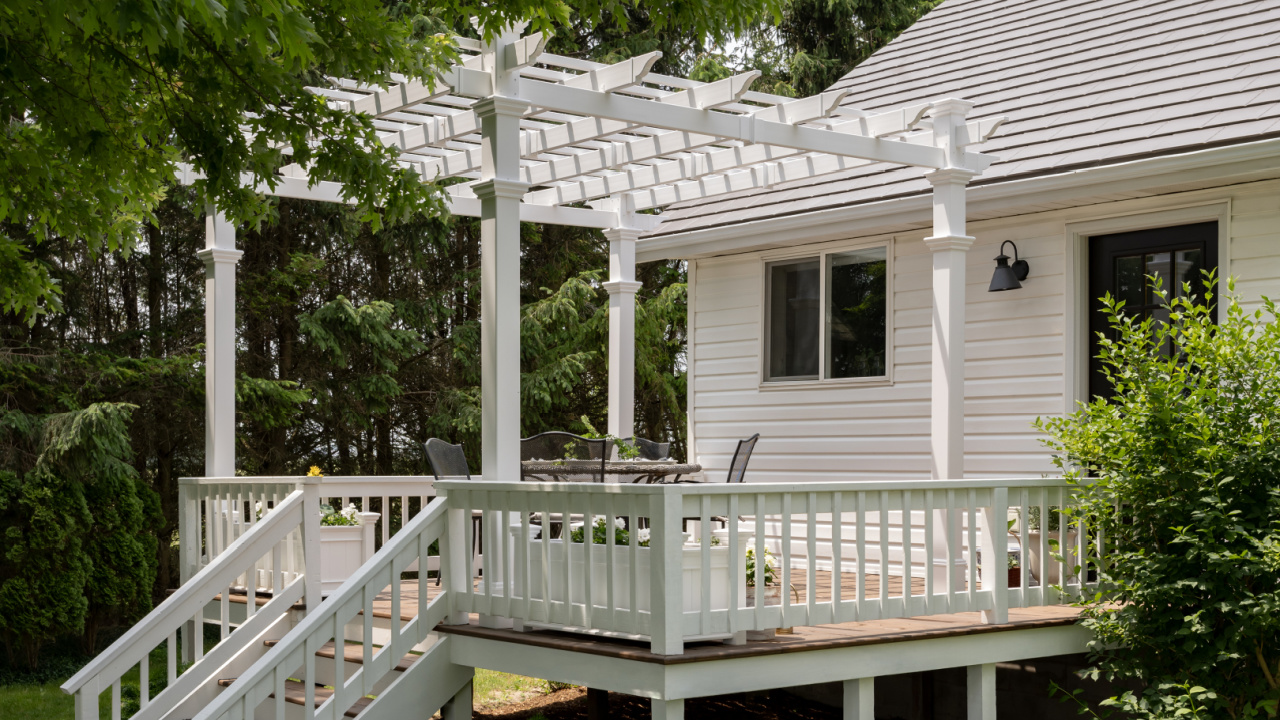 A creamy white sheepskin throw draped over a wooden porch railing in the shade, gently moving in a light breeze, cozy lifestyle photography