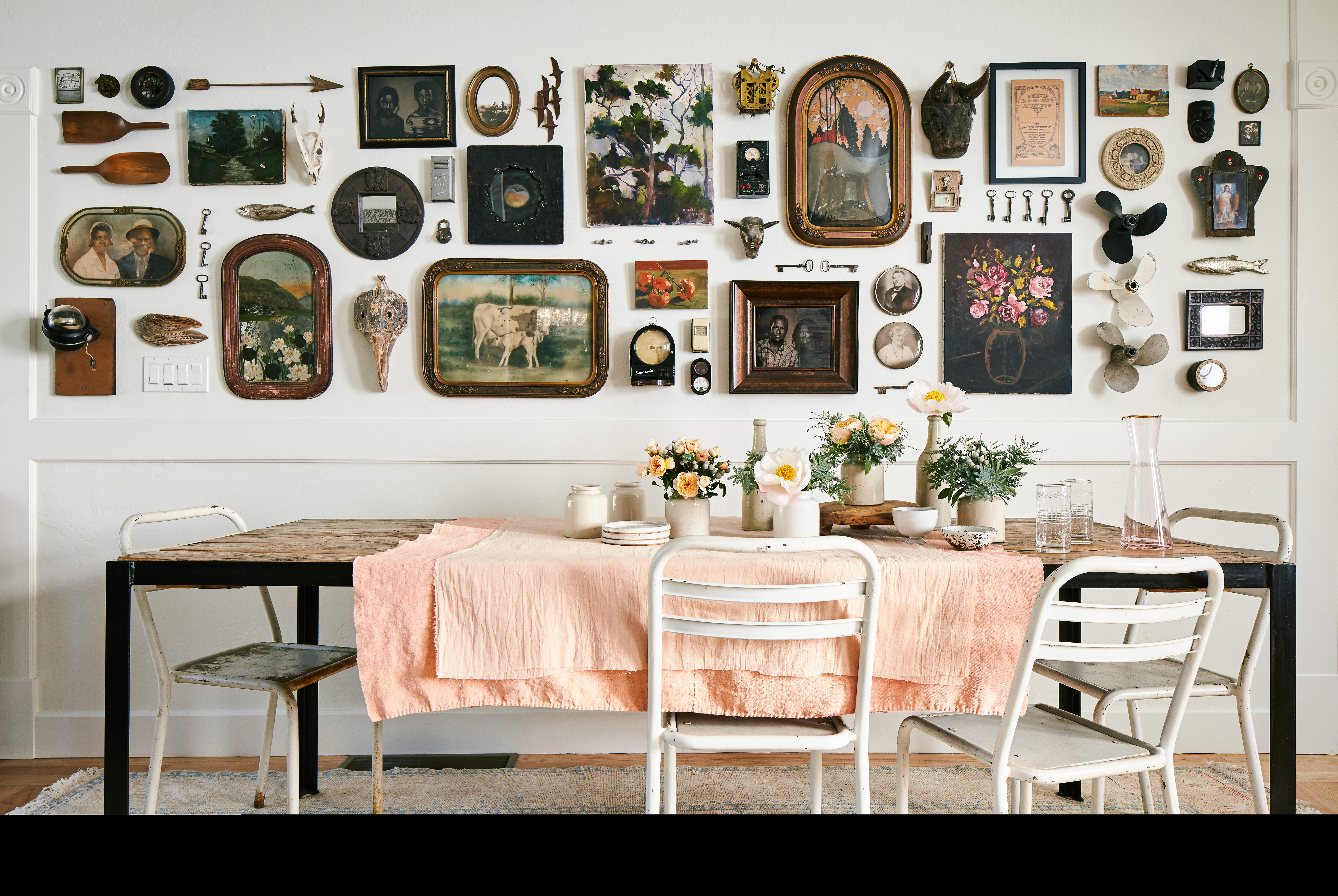 A dining room with a cohesive gallery wall of vintage frames above a sideboard, warm wood tones and soft natural light, realistic interior photograph