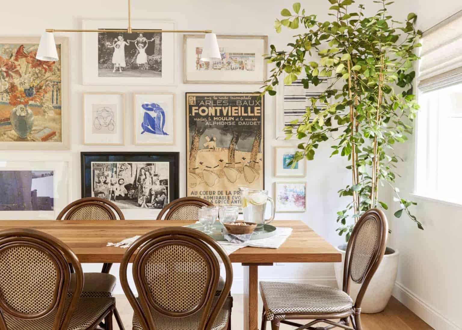 A gallery wall with a mix of wooden frames in similar warm undertones, hung above a sofa with a linen throw, real photography