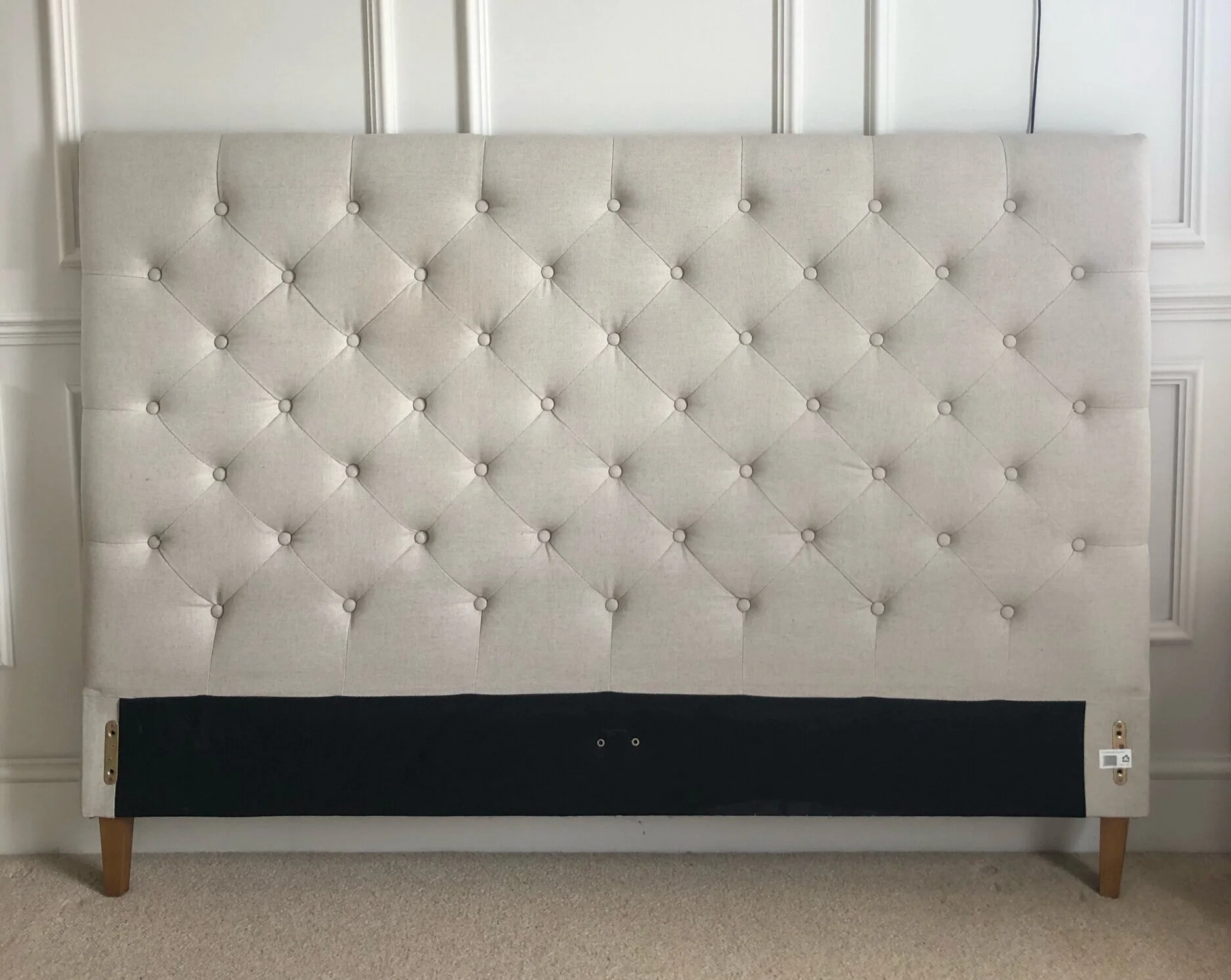 A headboard panel covered in white polyester batting, loosely draped and ready to be pulled taut and stapled on the backside