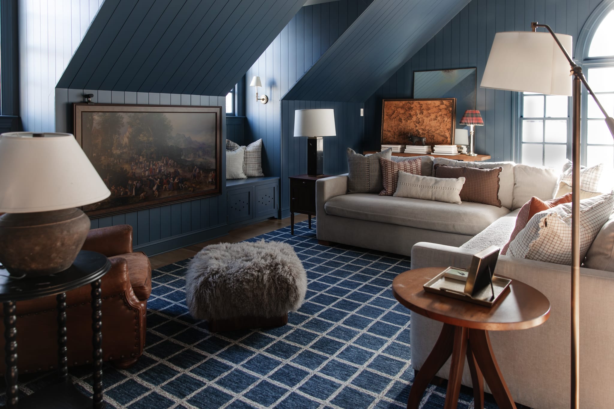 A living room vignette showing a patterned rug and coordinating pillows on a sofa, with visible shared colors like cream, blue, and caramel, natural light photo