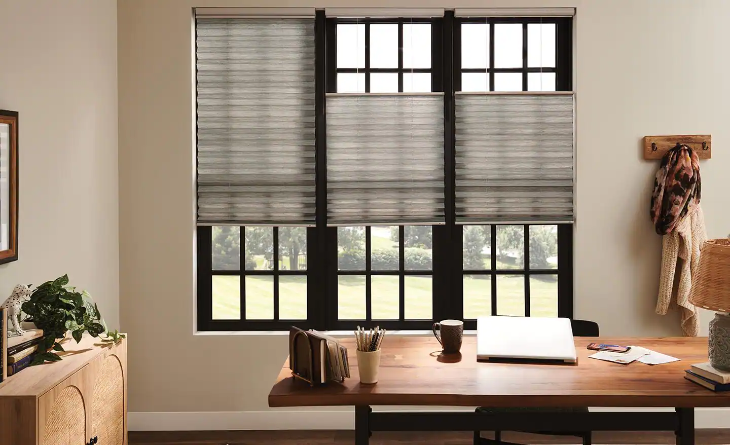 A living room window with a top-down bottom-up shade partially lowered from the top, allowing daylight while blocking the lower view, real photo