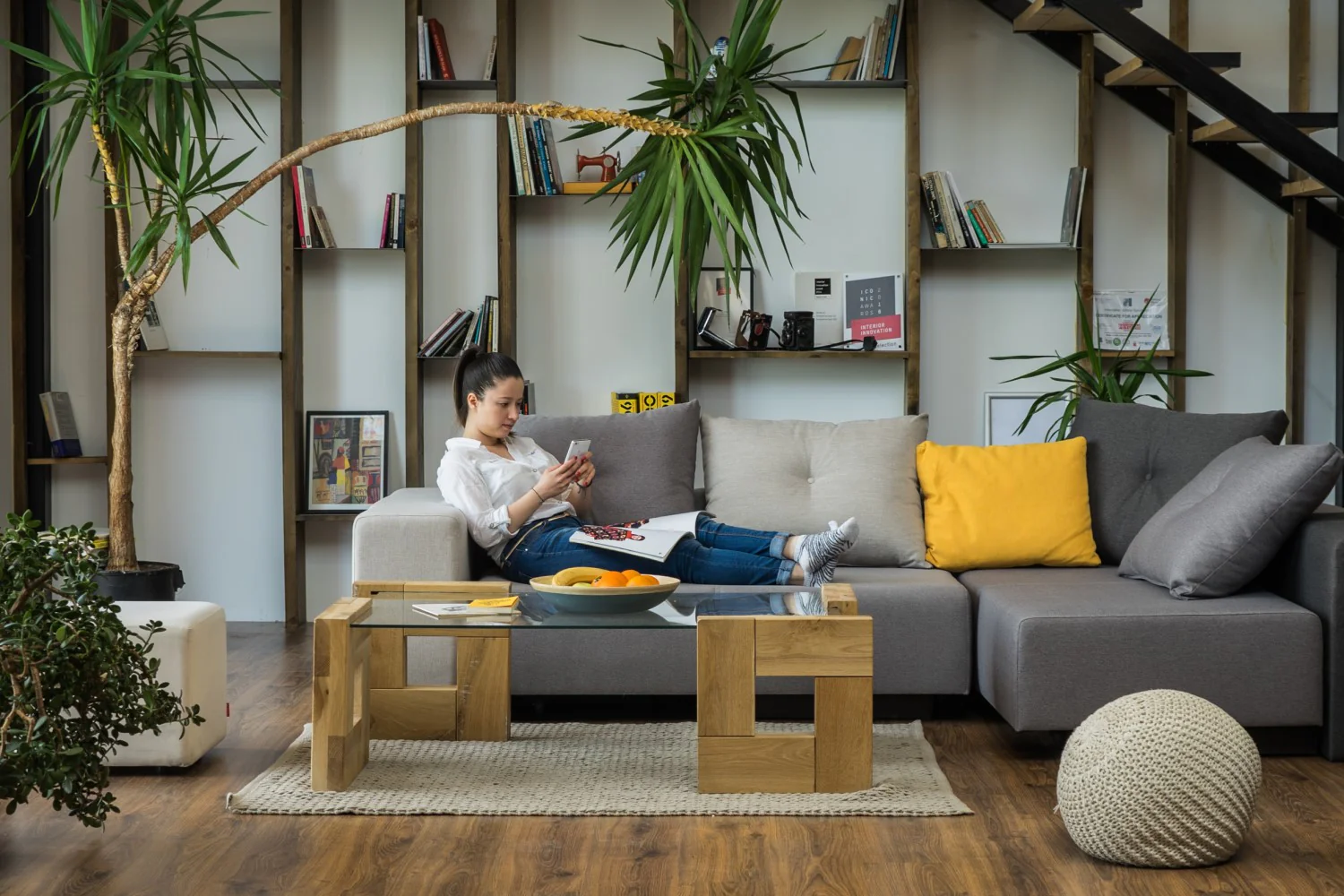 A neutral fabric sofa in a cozy winter living room with a knitted throw draped over the arm and a soft glowing table lamp nearby, real photograph style