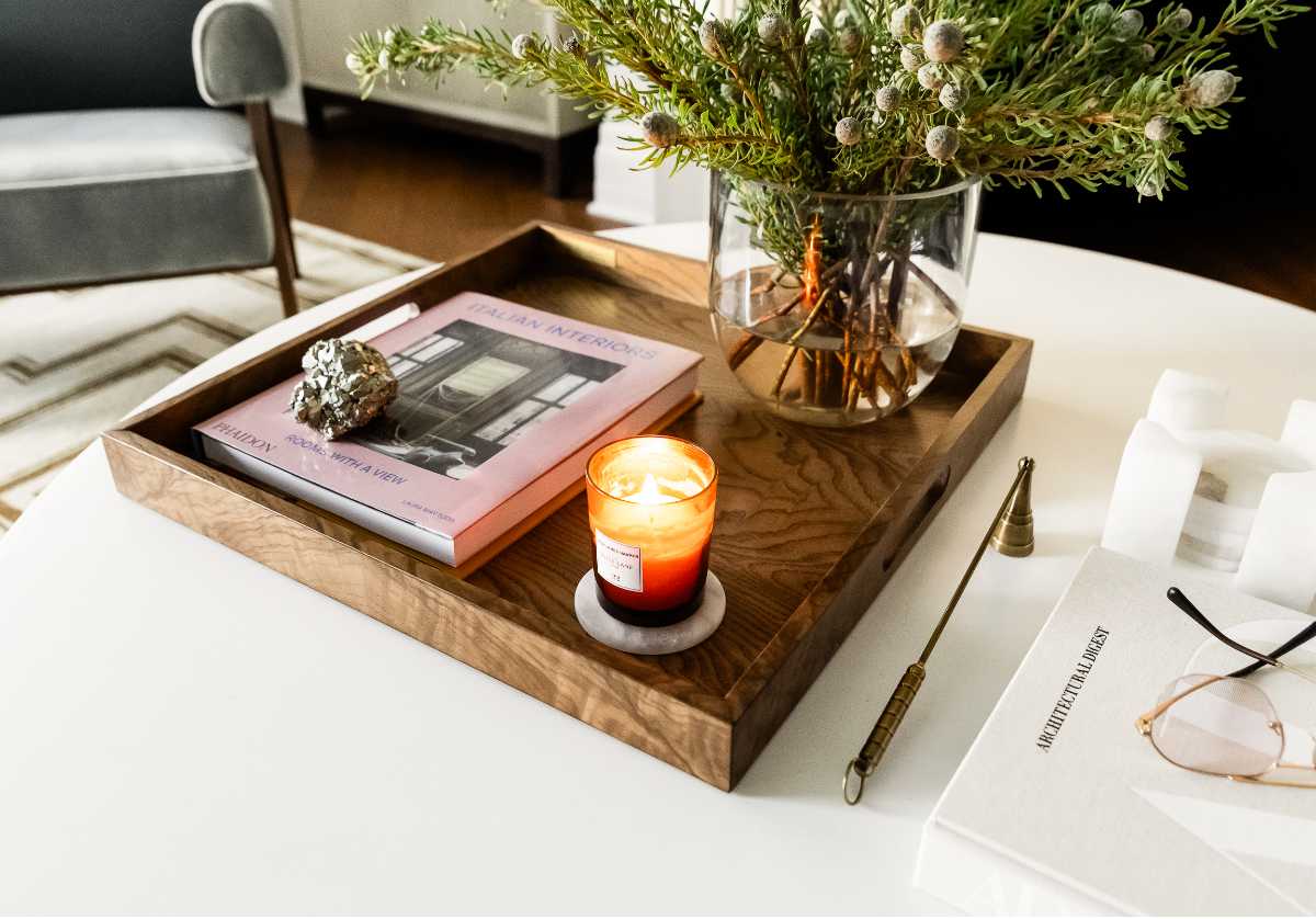 A photo of a brass tray holding a candle and matches on a wooden coffee table, positioned a safe distance from a cream sofa in a cozy living room