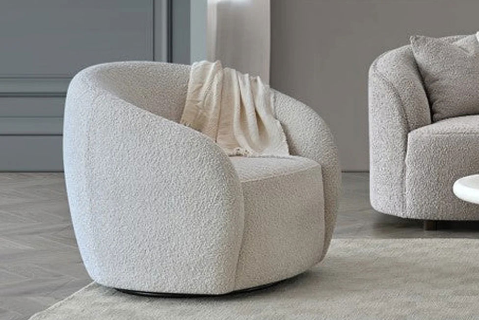 A photo of a light bouclé armchair being gently steamed from several inches away with a handheld garment steamer in a calm home setting