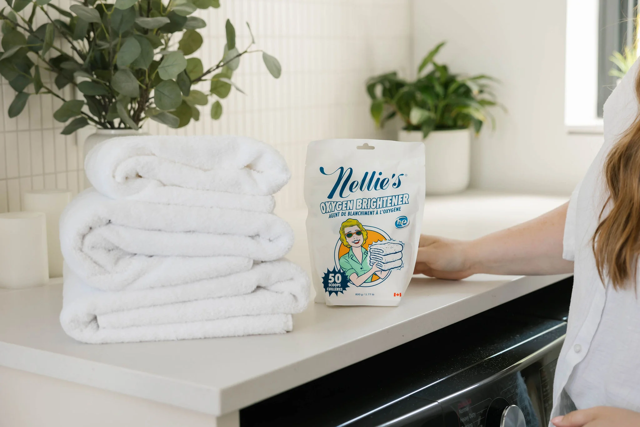 A photo of a scoop of oxygen bleach powder resting on a laundry counter beside a bowl of warm water, ready to be dissolved