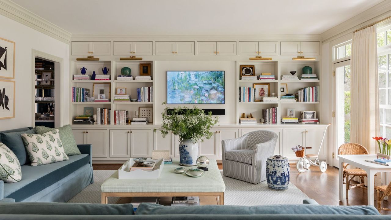 A real living room coffee table styled with a vintage brass tray, stacked hardcover books, a small vase of greenery, and a candle, warm afternoon light