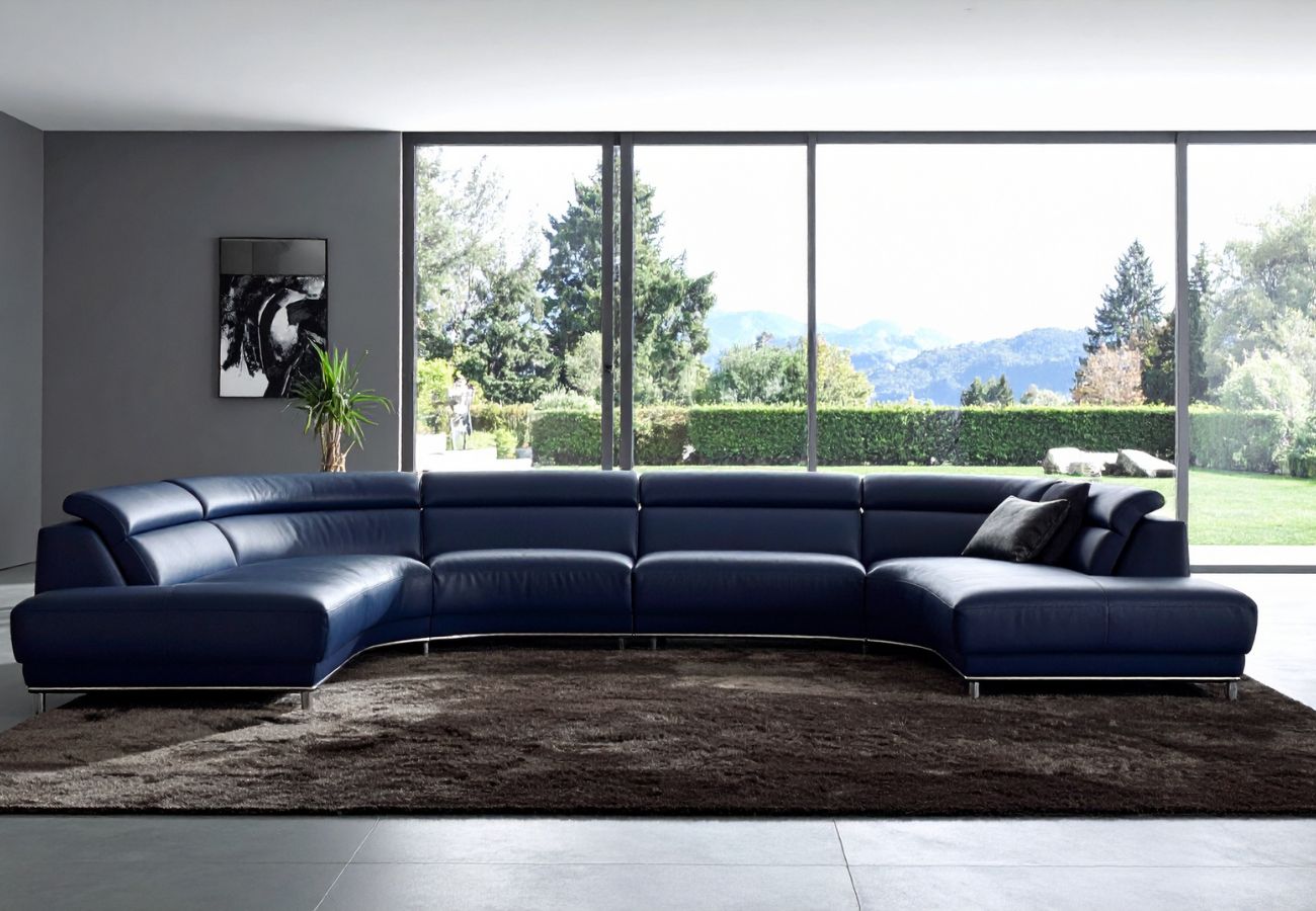 A real living room photograph showing a peeling faux leather sofa positioned near a bright window, with sunlight falling across the cracked seat area