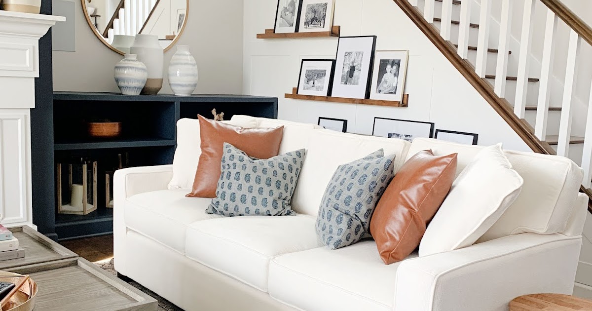 A real photo close-up of a white microfiber cloth folded into quarters resting on a neutral performance fabric sofa cushion beside a small bowl of water