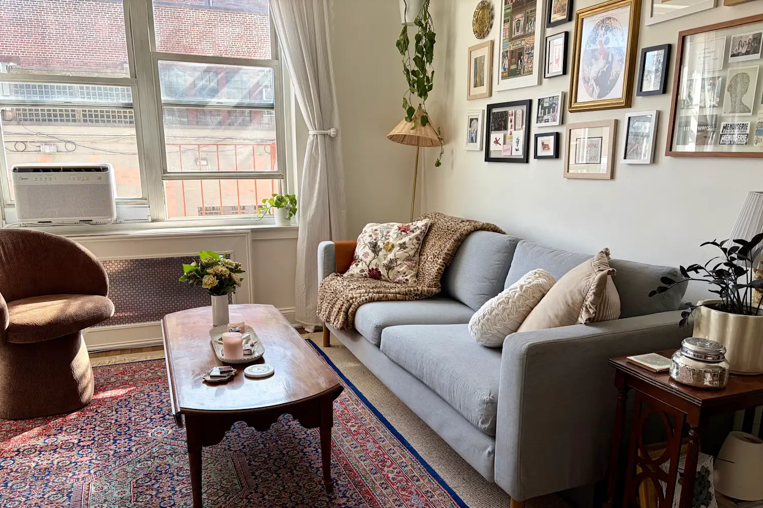 A real photo of a compact living room with a sofa and coffee table both sitting on a large neutral rug, creating a clear walkway and a soft landing area