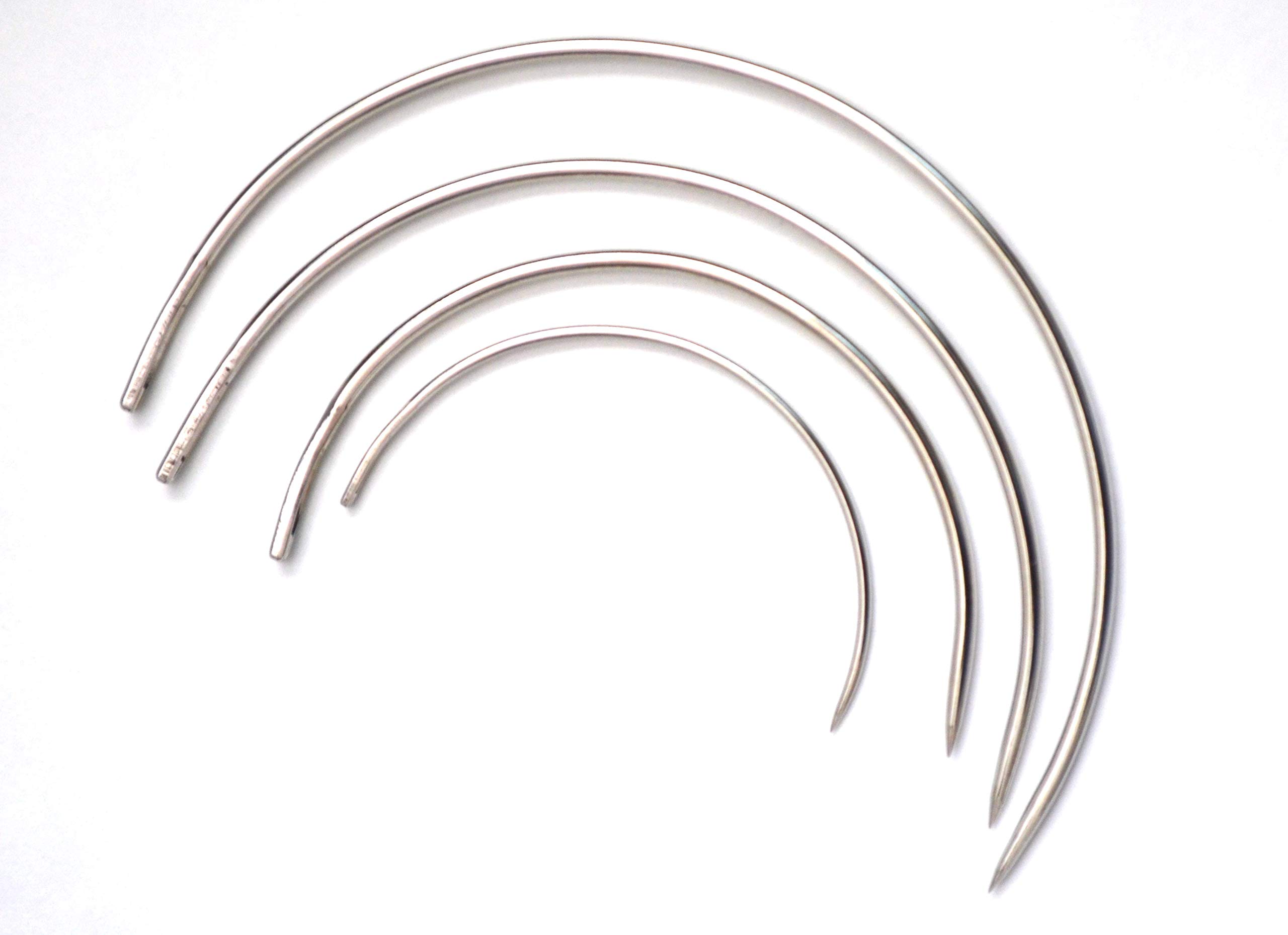 A real photo of a curved upholstery needle beside a spool of heavy-duty polyester thread and small fabric clips on a wooden table