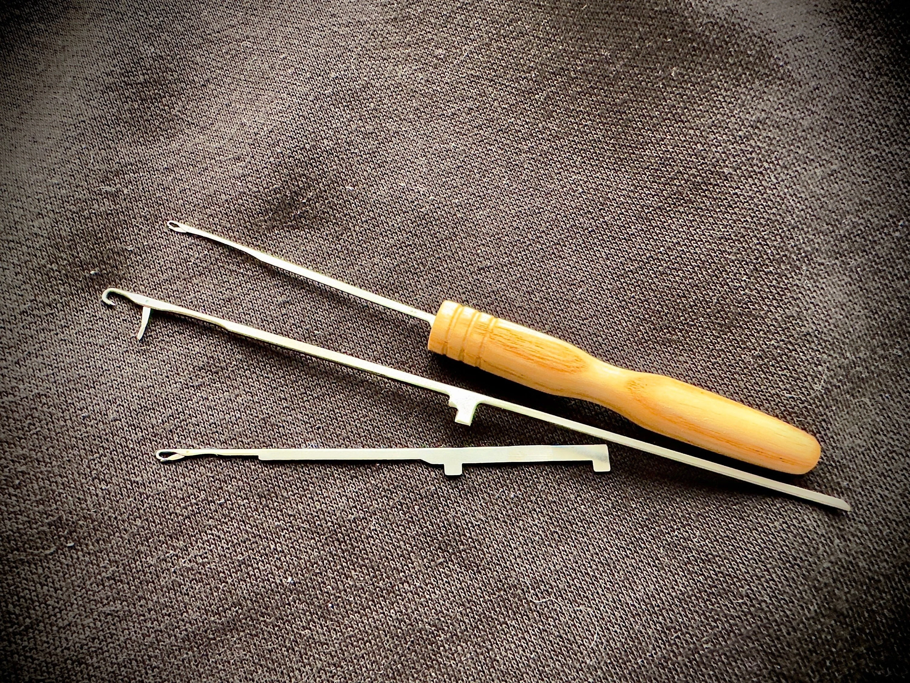 A real photo of a hand holding a small latch hook tool above a textured sofa fabric, ready to pull a snagged loop through to the underside