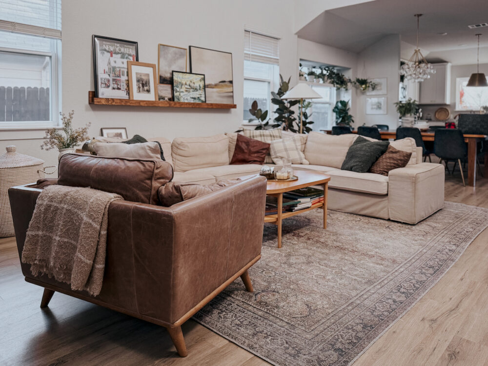 A real photo of a neutral fabric sofa in a cozy living room with a textured knit throw draped casually over one arm in warm evening light