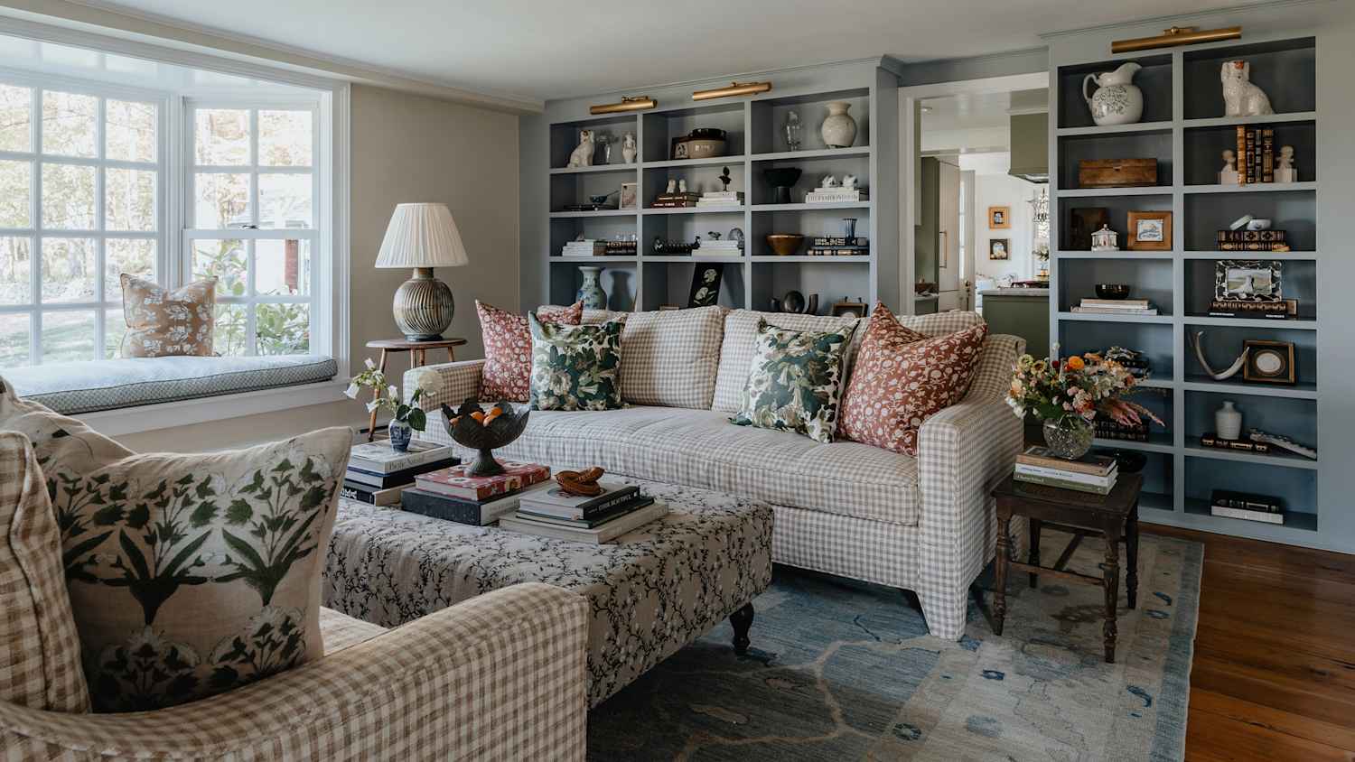 A real photo of a small apartment living room with a neutral sofa, a subtle clear corner guard on the front sofa arm, and warm ambient lighting from a table lamp