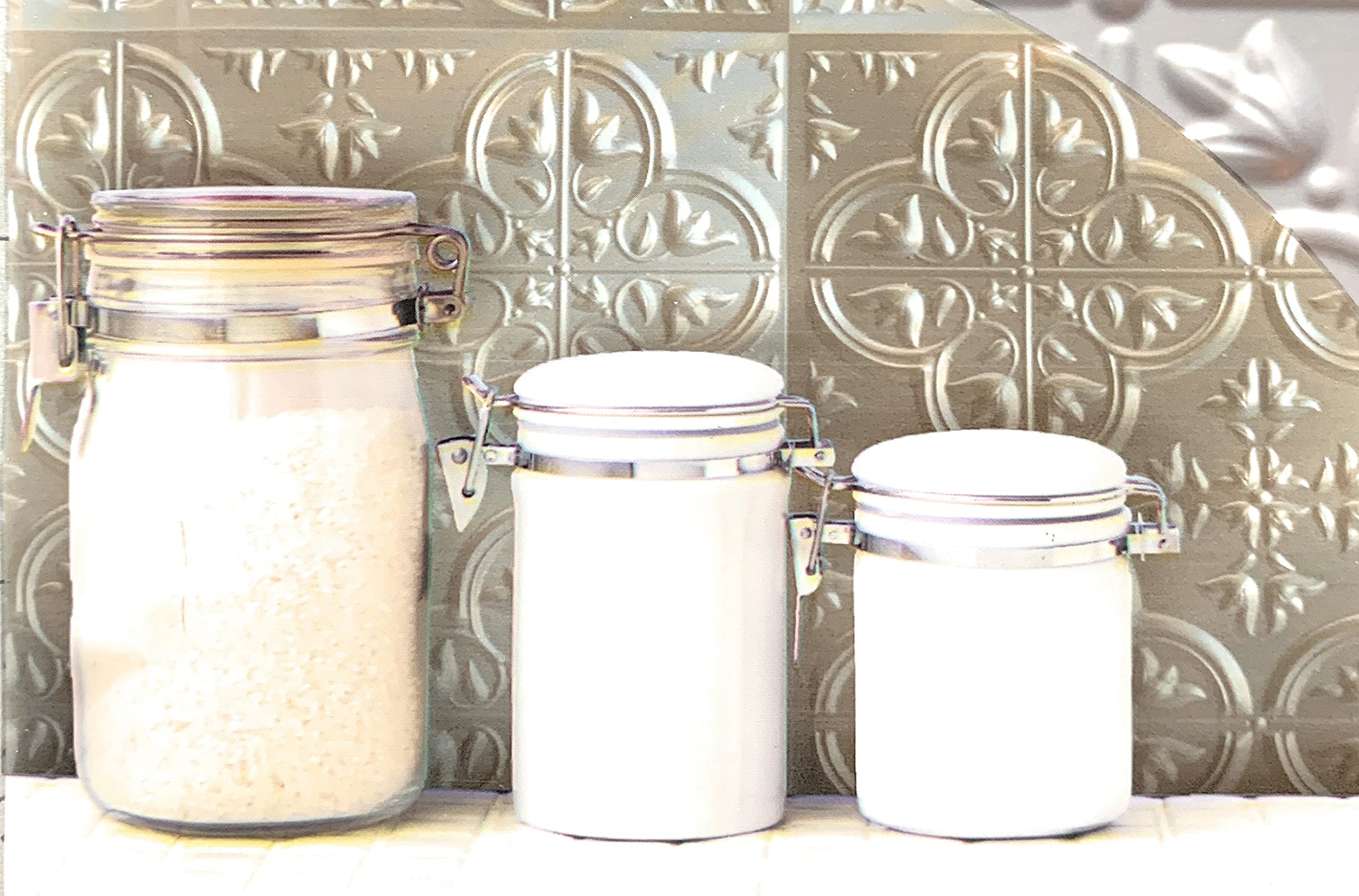 A real photo of a small kitchen corner with a peel-and-stick tin-style metal backsplash in an antique brass tone, reflecting warm lamp light and paired with vintage canisters