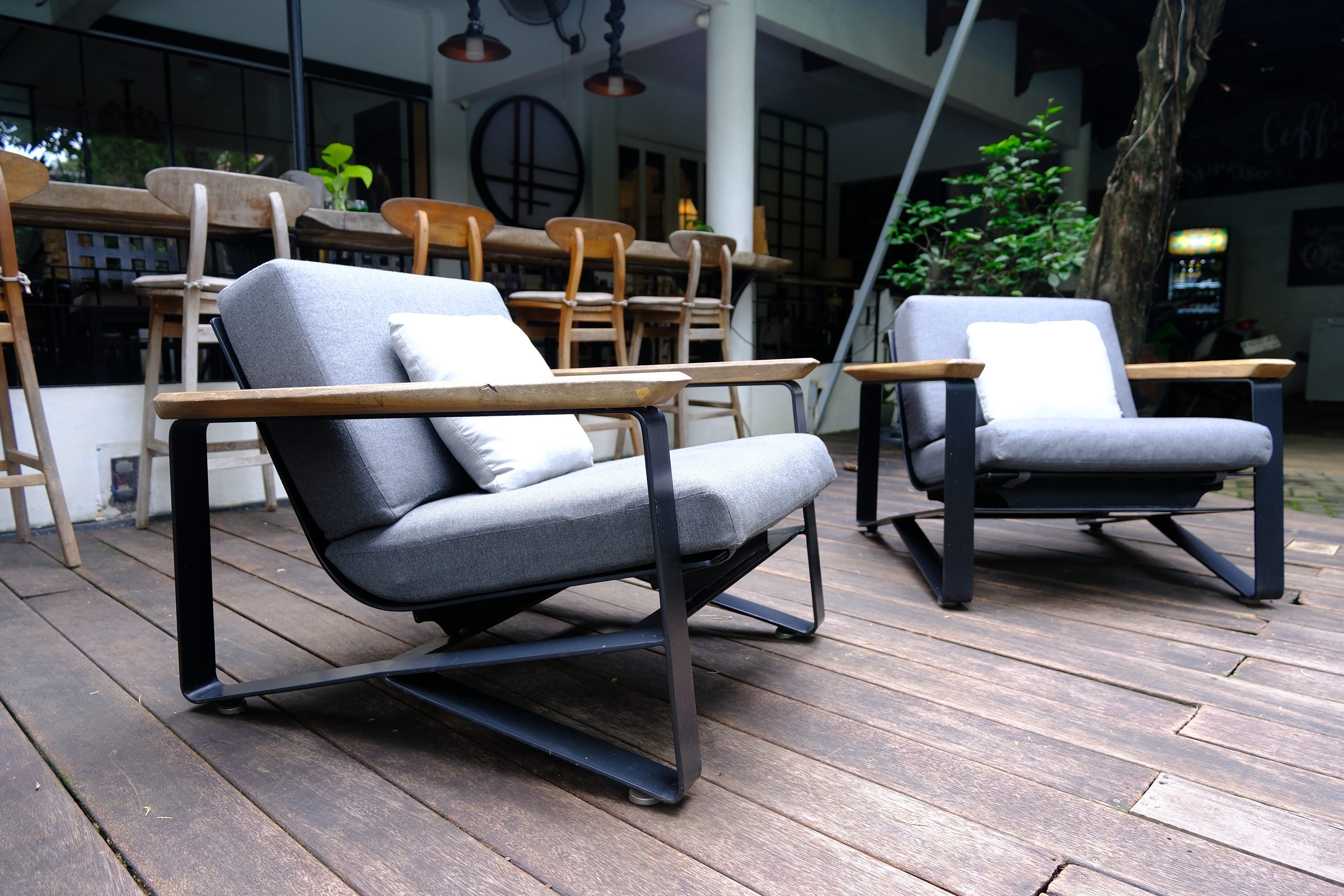 A real photo of a sofa cushion standing on its edge on a clean floor with a small fan nearby to circulate air for even drying