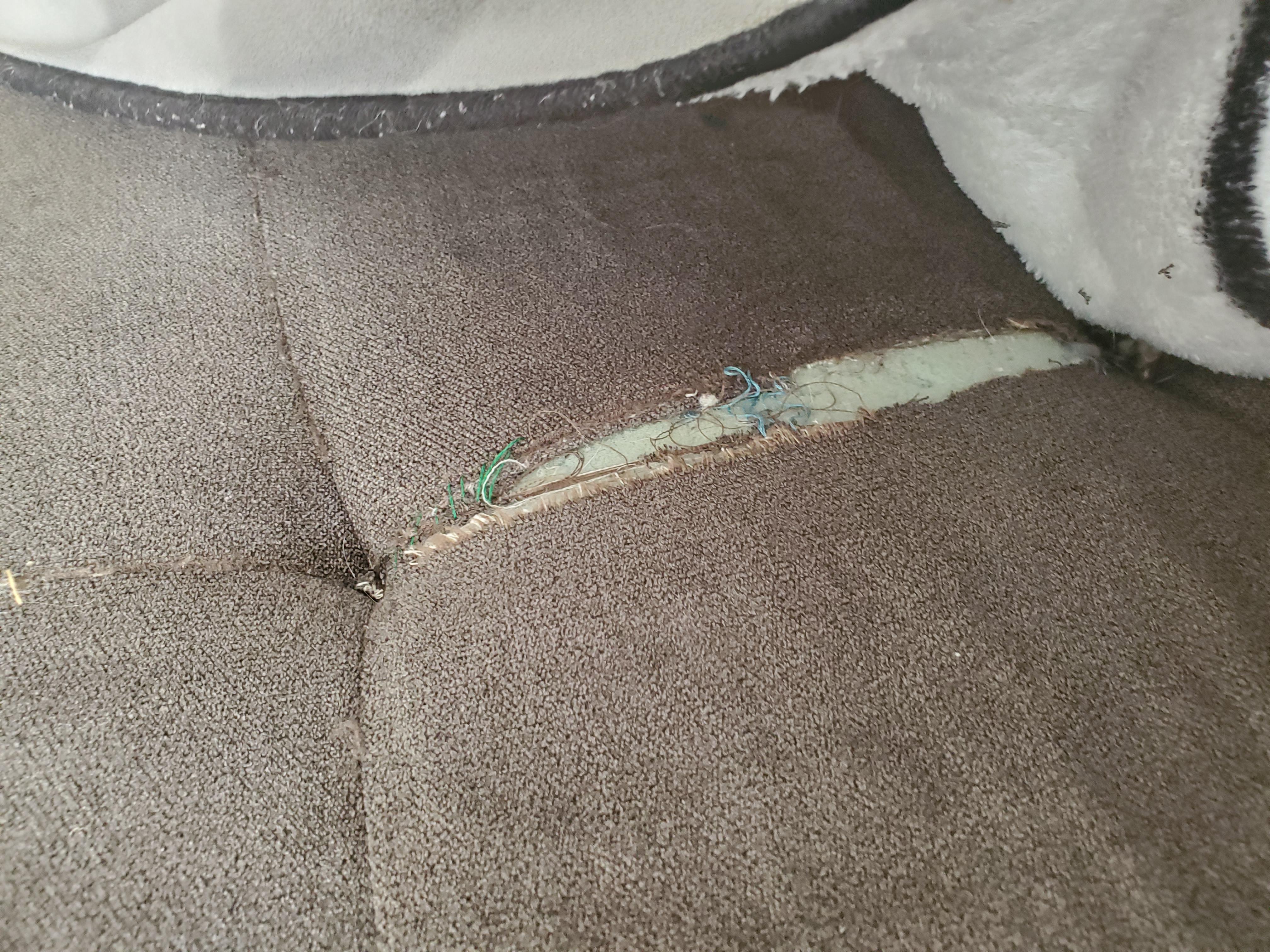 A real photo of a sofa cushion with a freshly repaired seam lying flat on a couch, the seam closed and smooth on textured neutral upholstery