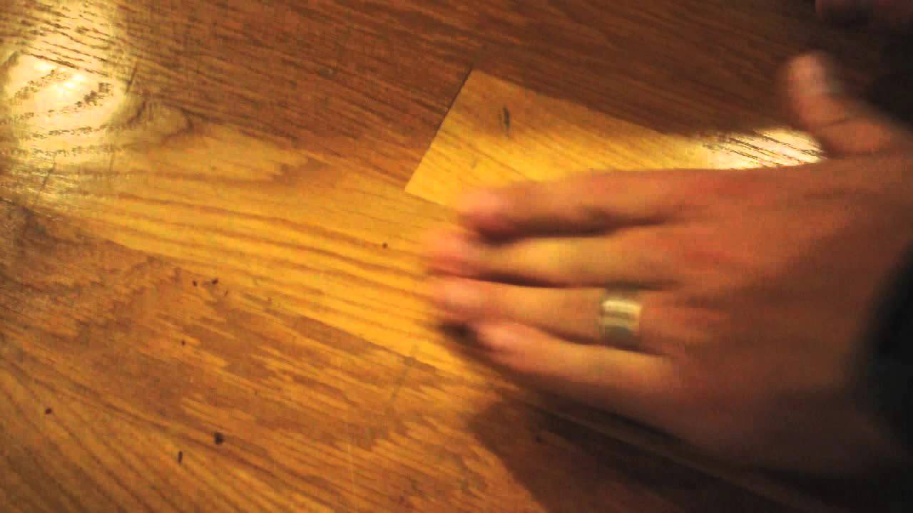 A real photo of a white vinyl eraser and a microfiber cloth resting beside a small heel mark on a finished oak floor