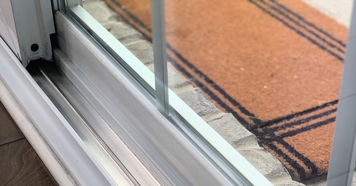 A real photo of an apartment window lower track being cleaned with a small soft brush and a microfiber cloth nearby, natural daylight
