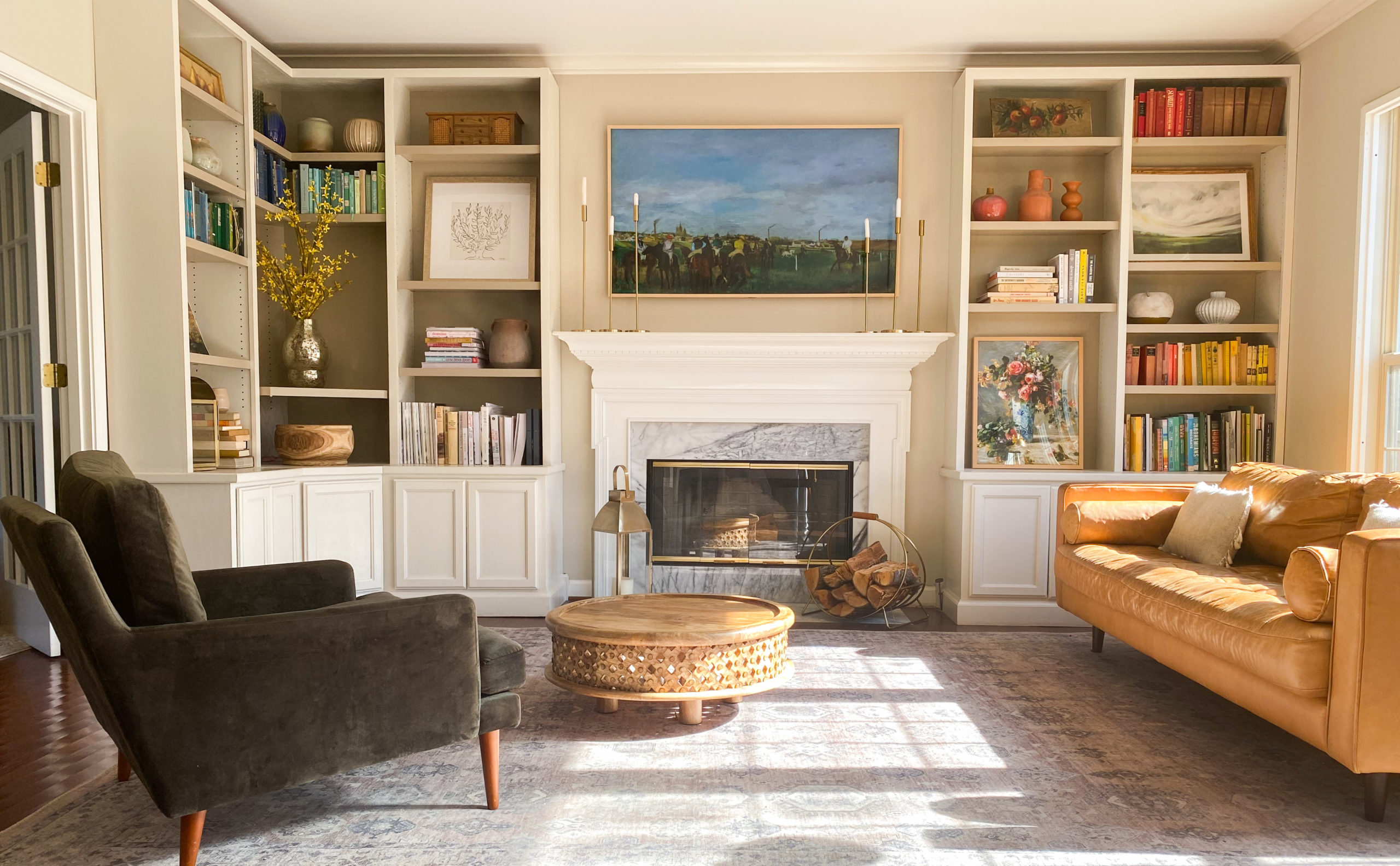 A real photo of crown molding being installed along the top of built-in bookshelves, a mitered corner visible, with a nail gun in use