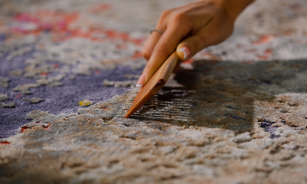 A real photo of hands sprinkling baking soda from a small bowl onto a light-colored area rug in a bright home interior, simple cleaning moment