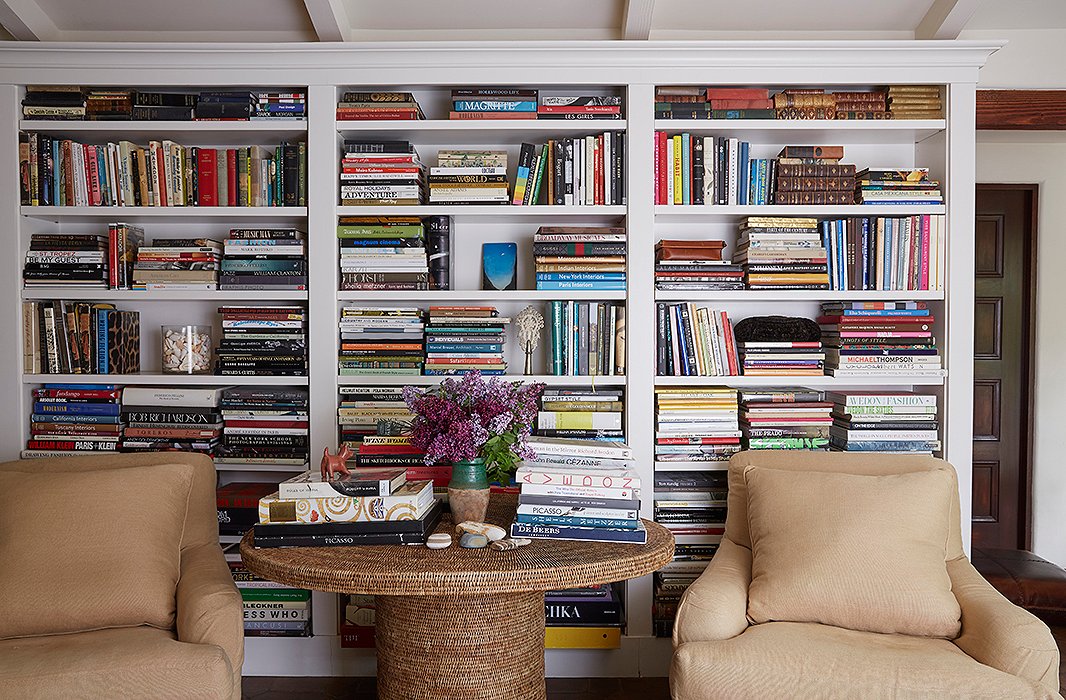 A real photograph close-up of a bookshelf showing vertically shelved books next to a neat horizontal stack topped with a small ceramic bowl, with a few inches of empty space for balance