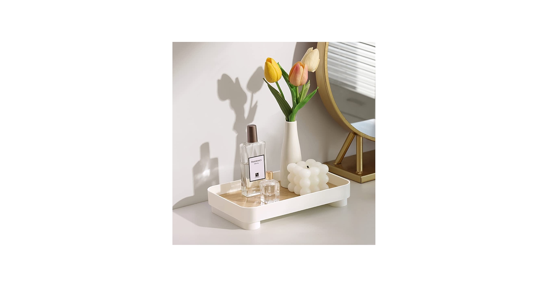 A real photograph of a bathroom vanity with a small philodendron in a warm ceramic pot placed beside a stone tray holding soap and a toothbrush, soft warm lighting