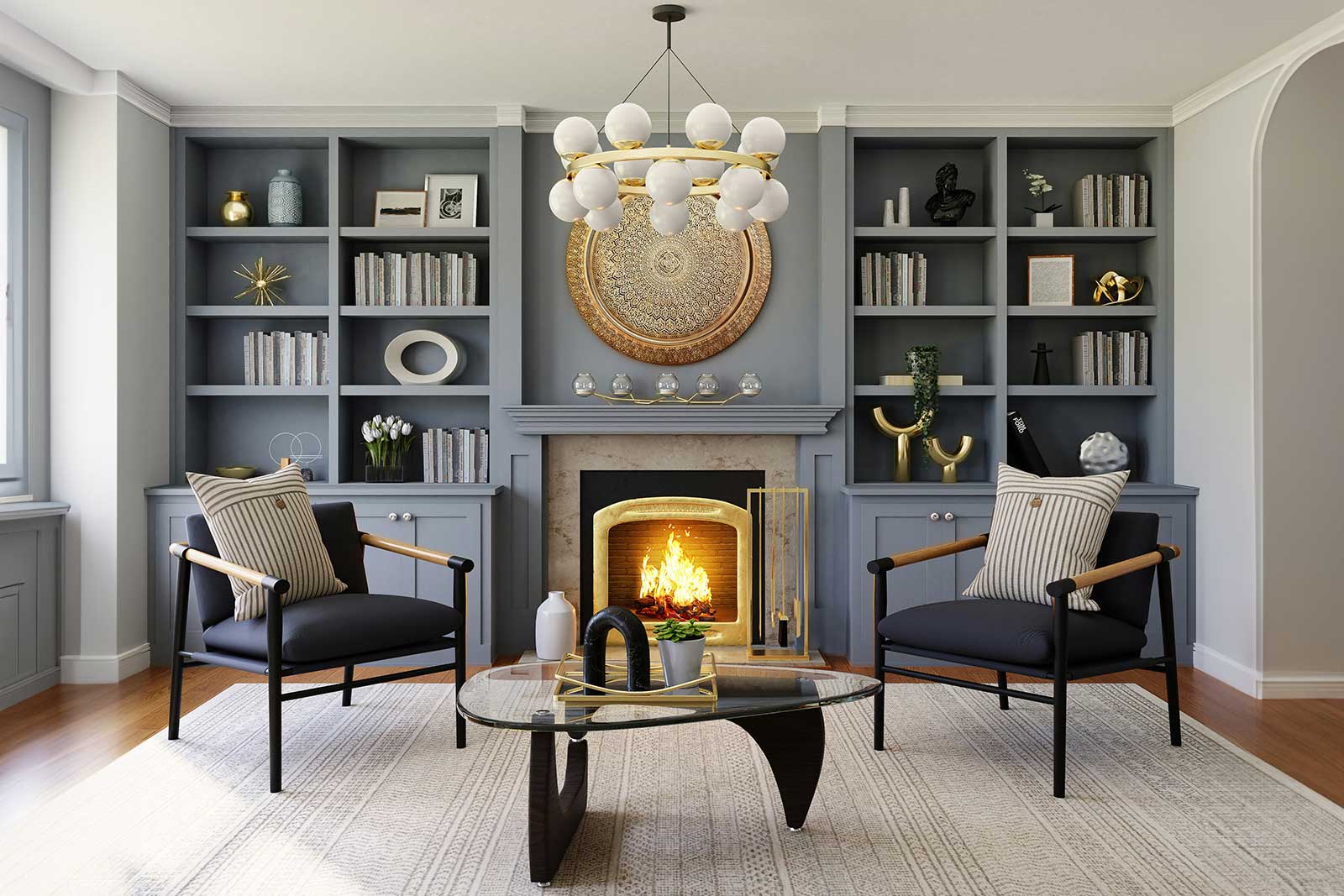 A real photograph of a bookshelf shelf with two framed artworks leaning and slightly overlapping at the back, a stack of books in the middle, and a small brass object in the foreground under warm lamplight