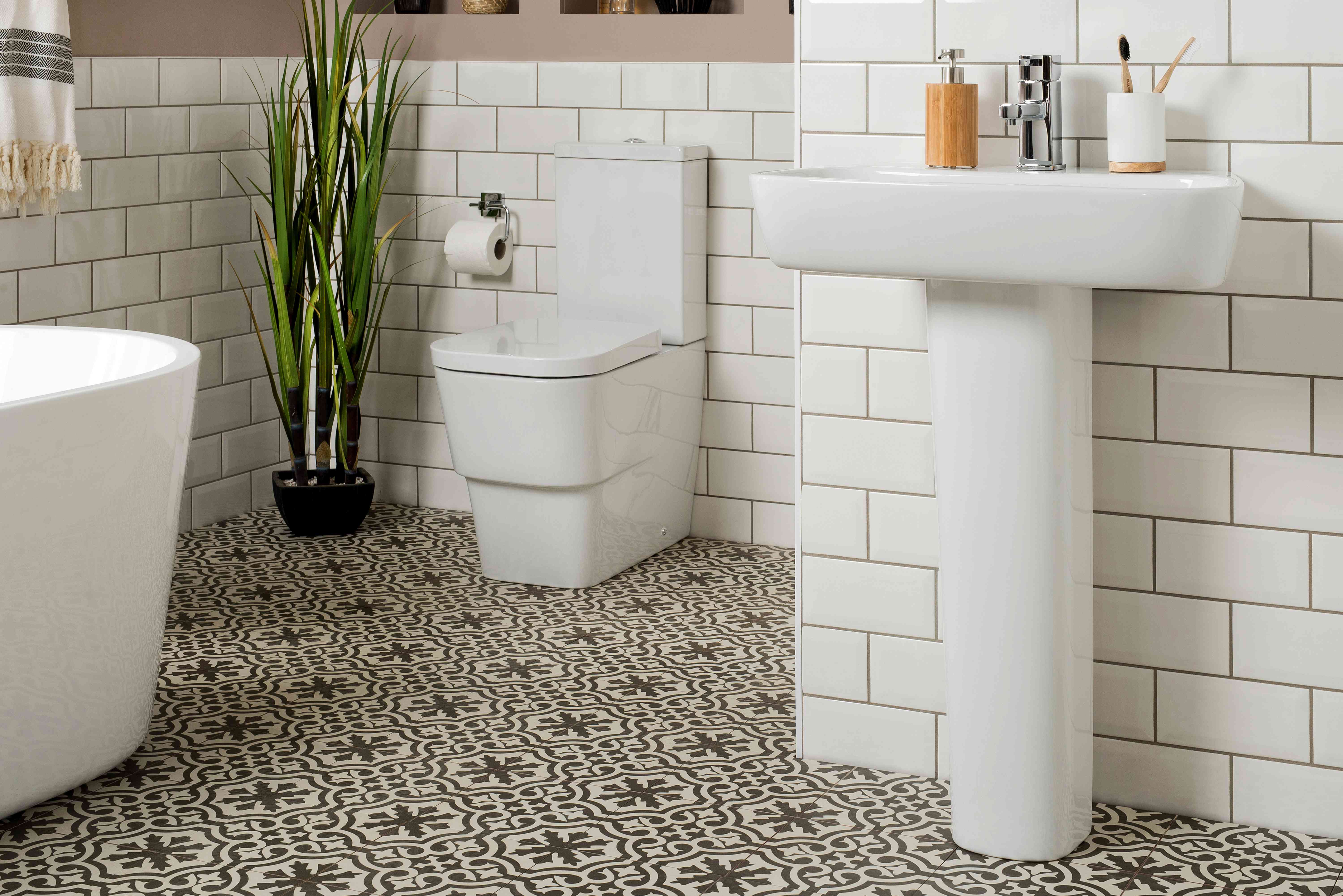A real photograph of a classic white pedestal sink with a slim wrap-around metal storage caddy holding towels and toiletries in a small bathroom