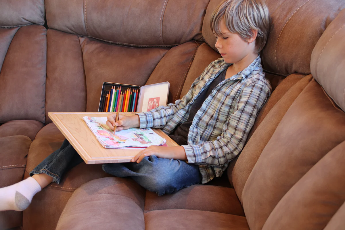 A real photograph of a cozy living room with a fabric sofa where child-friendly craft supplies like paper and glue sticks are placed on a tray on the cushion, warm ambient lighting