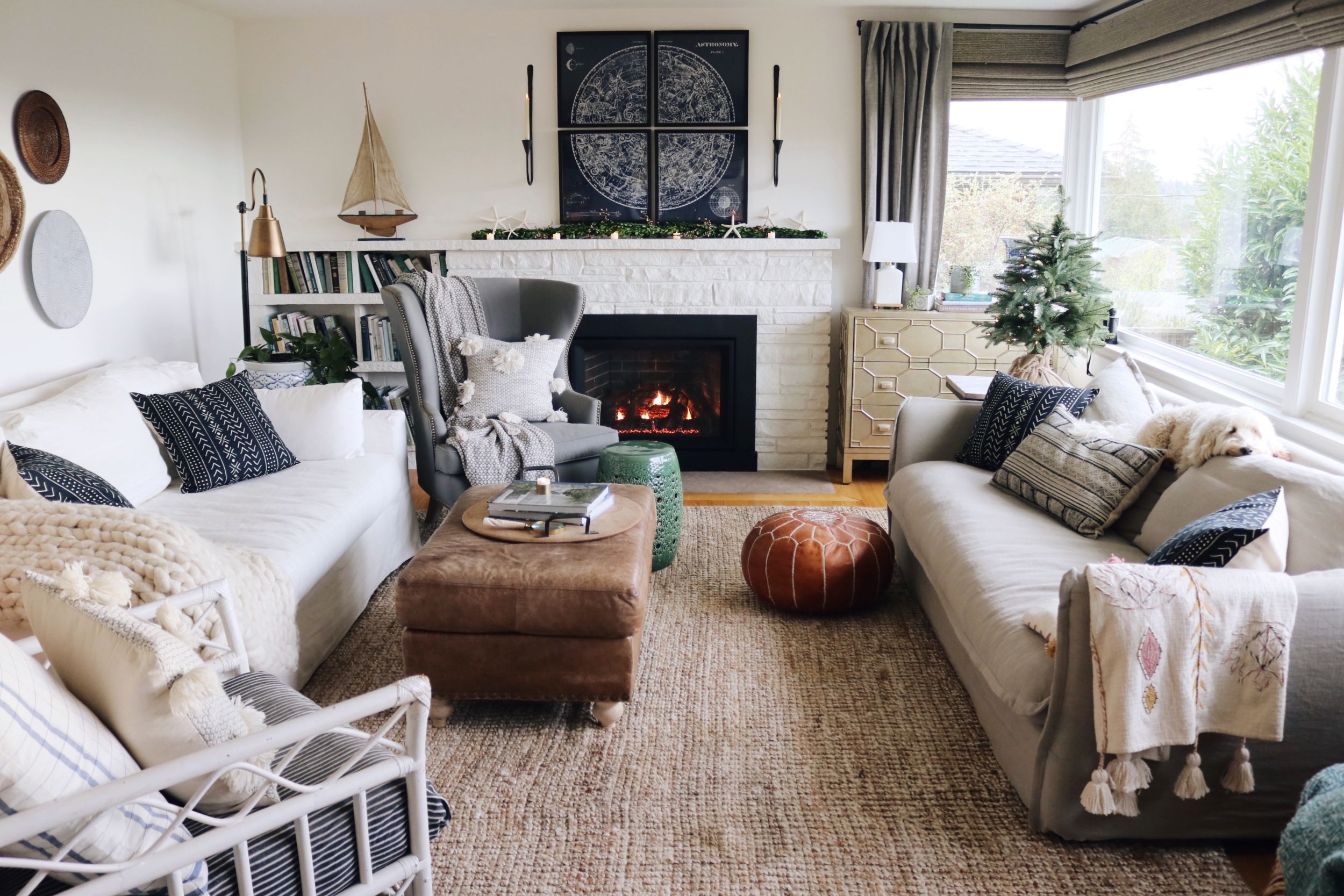 A real photograph of a cozy living room with a sofa styled with linen pillows and a soft throw blanket, warm lamplight in the background