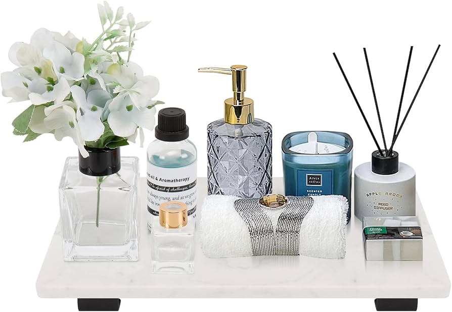 A real photograph of a small ceramic tray holding hand soap and a sponge on a marble countertop beside a kitchen sink