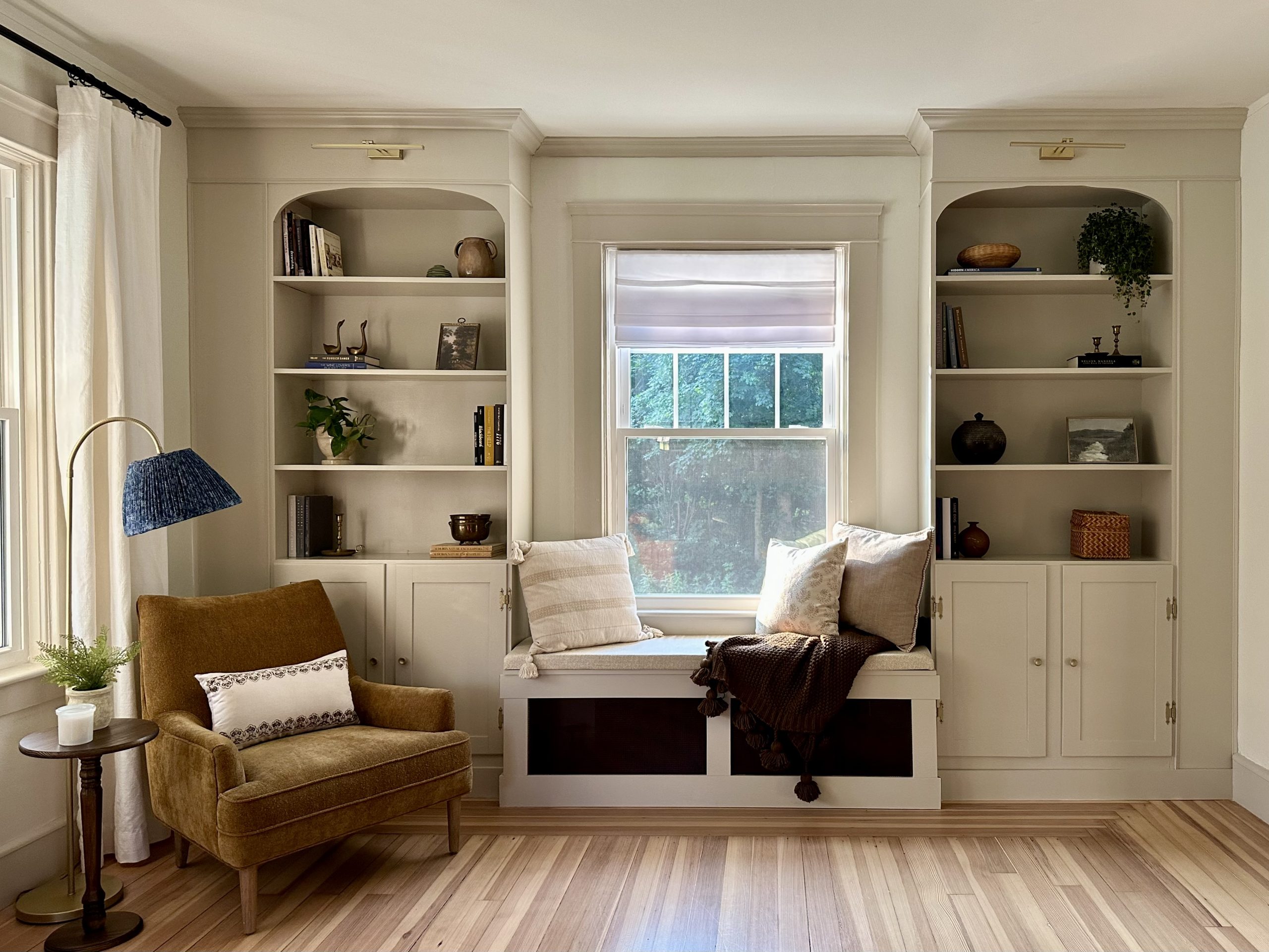 A real photograph of a tall shelving unit with smooth side panels and top trim, painted to match the wall for a built-in appearance