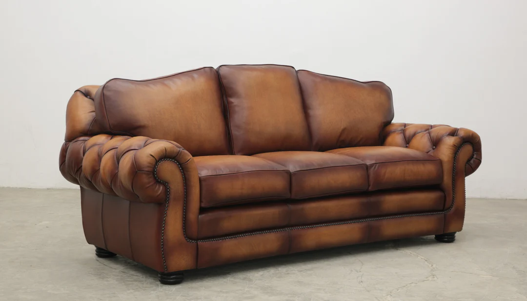 A real photograph of a well-kept vintage brown leather sofa sitting in a secondhand furniture shop with warm indoor lighting