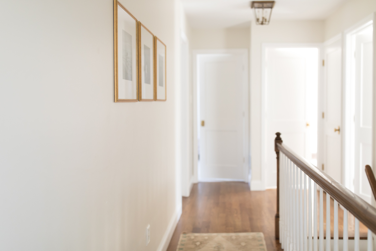 A realistic photo of an older home hallway with slightly yellowed white door trim while a small sanded spot has been prepped for touch-up paint