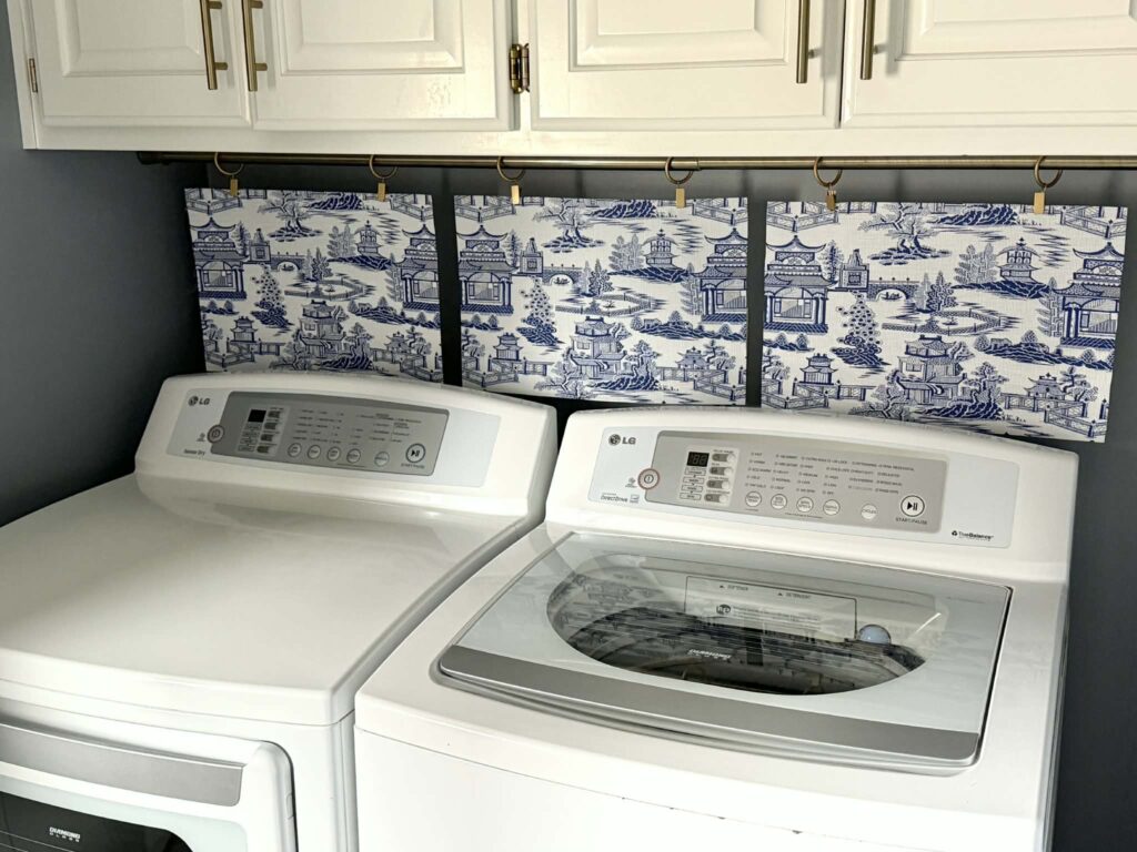 A realistic photo of white curtains being placed into a front-loading washing machine in a bright laundry room