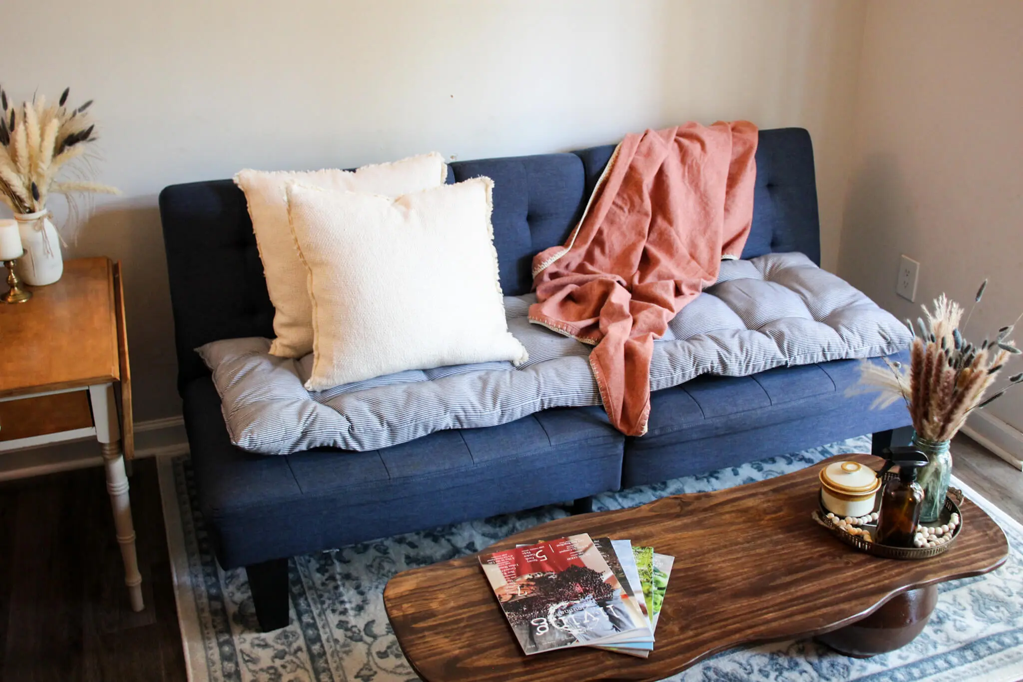 A realistic photograph of hands gently pressing a small feather quill back into a sofa cushion cover, focusing on the fabric texture and careful motion