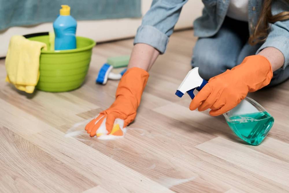 A renter mopping a small kitchen with an older sheet vinyl floor using a microfiber mop and a bucket, natural window light, realistic home photo