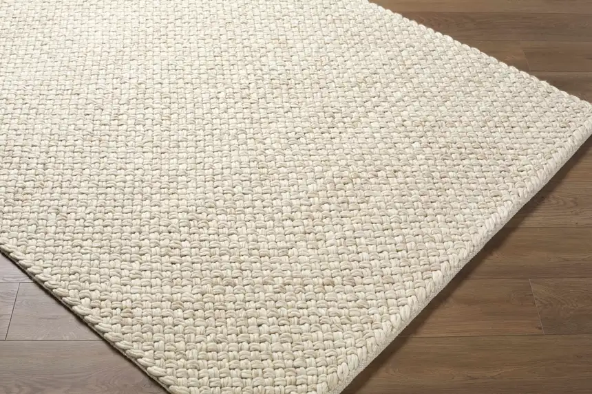 A rolled-out wool area rug hanging over a sturdy clothesline outdoors in open shade, with gentle breeze and no direct sun