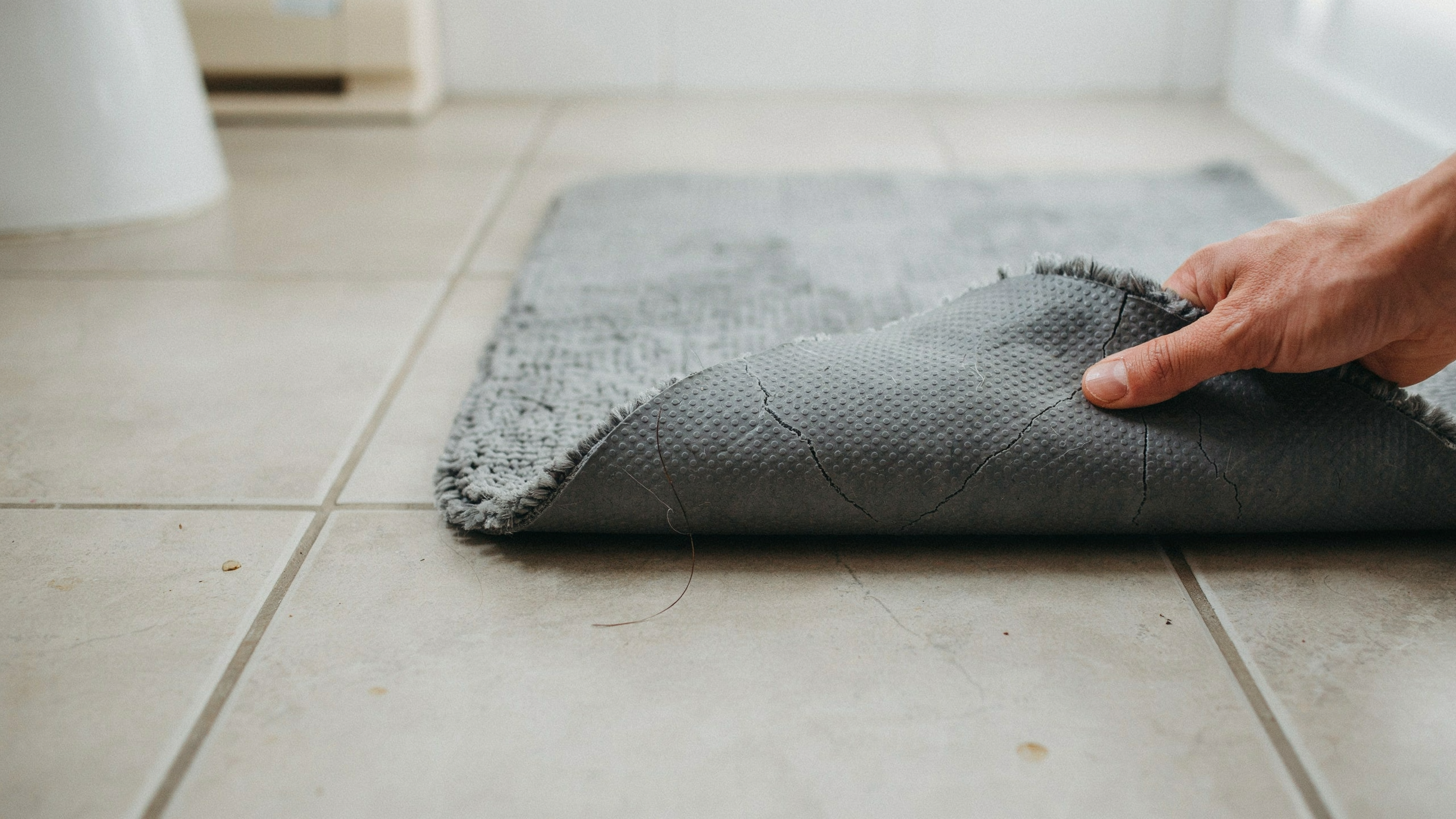 A rug corner with a deteriorating rubber backing that is cracking and flaking