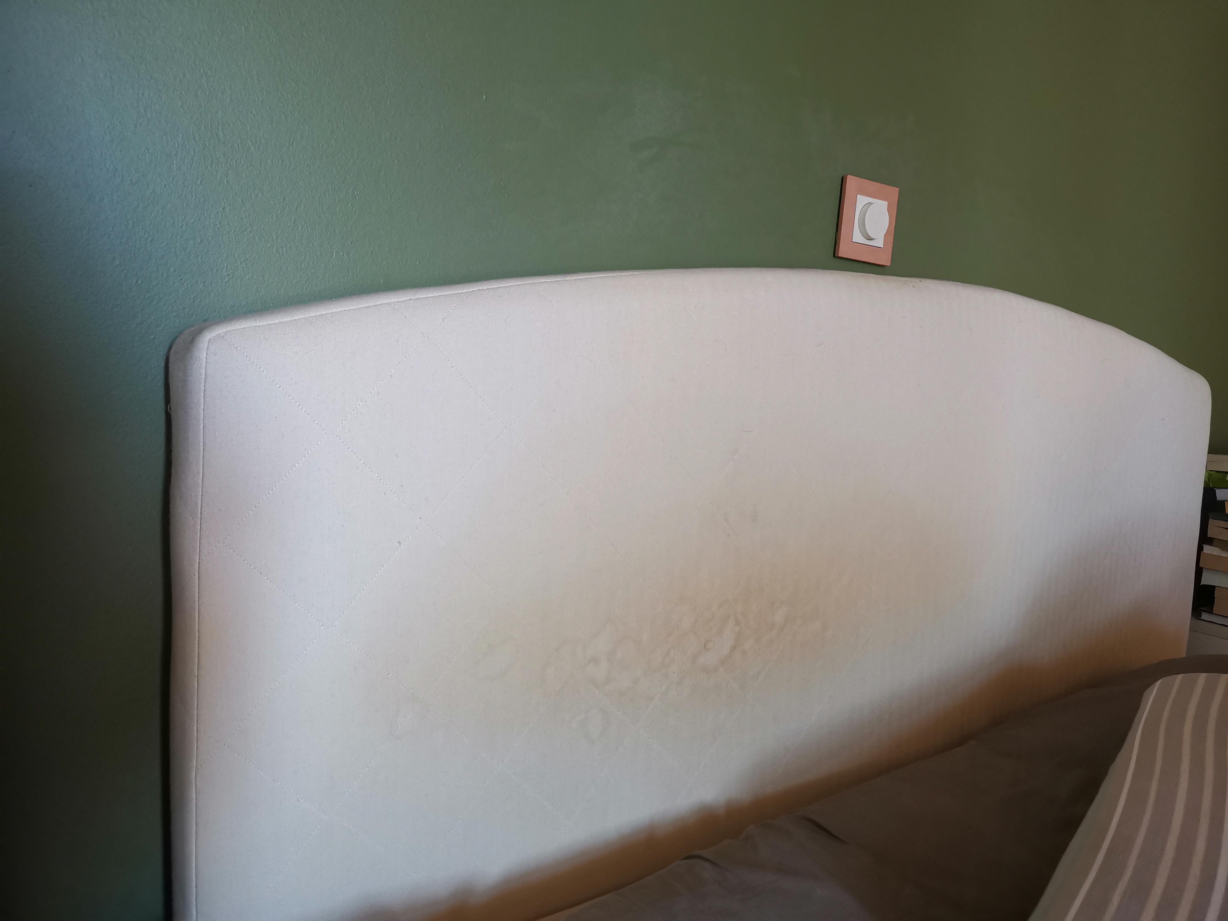 A small fan on a nightstand aimed toward a fabric headboard to speed drying after spot cleaning, cozy bedroom photo